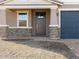 A close-up view of this home's front door, showing the stonework, garage door and desert landscaping at 17737 W Elm St, Goodyear, AZ 85395