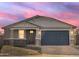 A dusk shot of this single-story home showcases the stonework, garage and desert landscaping at 17737 W Elm St, Goodyear, AZ 85395