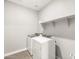 Laundry room featuring modern appliances, tile flooring, and overhead shelving at 17749 W Elm St, Goodyear, AZ 85395