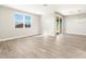 Spacious living room with wood-look tile floors, large windows, and a sliding glass door at 17749 W Elm St, Goodyear, AZ 85395