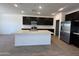 The kitchen features black cabinets, a white island, and stainless steel appliances at 47267 W Mellen Ln, Maricopa, AZ 85139
