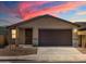 Beautiful single-story home with a two-car garage against a vibrant sunset backdrop at 9120 N 174Th Ln, Waddell, AZ 85355