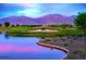 Scenic golf course view featuring a serene lake and a sand trap against a mountain backdrop at 11899 N Spearfish St, Surprise, AZ 85388