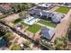 Stunning aerial view of a modern home, tennis court, and luxurious pool surrounded by green lawns and desert landscaping at 6215 N Casa Blanca Dr, Paradise Valley, AZ 85253
