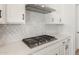 Close-up of a stove top with a modern range hood and stylish backsplash in the well-appointed kitchen at 7682 W Mockingbird Way, Florence, AZ 85132