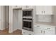 Kitchen features stainless steel built-in oven and microwave, white cabinets with black hardware, and light countertops at 7682 W Mockingbird Way, Florence, AZ 85132