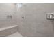 Walk-in shower featuring light tile surround, a built in bench, and shower niche at 7736 W Mockingbird Way, Florence, AZ 85132