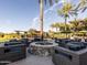 Outdoor lounge area with a stone fire pit and comfortable seating under palm trees at 28831 N 128Th Dr, Peoria, AZ 85383