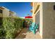 This cozy patio space with seating overlooks lush greenery and a red umbrella in the background at 4600 N 68Th St # 313, Scottsdale, AZ 85251