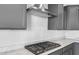 Close-up view of stainless steel range hood and cooktop over gray cabinets with sleek countertops at 24691 N 169Th Ave, Surprise, AZ 85387