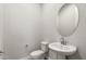 This powder room features a pedestal sink with round mirror and modern toilet at 24707 N 169Th Ave, Surprise, AZ 85387