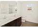 Bathroom with dual sinks, white countertops, dark cabinets and wood-look tile floor at 22507 W Pontiac Dr, Surprise, AZ 85387