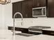 Close-up of kitchen showcasing stainless steel appliances, dark wood cabinetry, and a stylish faucet at 22507 W Pontiac Dr, Surprise, AZ 85387