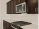 Close-up of modern kitchen, featuring sleek stainless steel microwave and oven, white subway tile and dark cabinetry at 22507 W Pontiac Dr, Surprise, AZ 85387