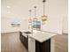 Kitchen island with stainless steel sink, quartz countertops, and pendant lighting overlooking a spacious living area at 22507 W Pontiac Dr, Surprise, AZ 85387