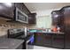 Modern kitchen with dark wood cabinets, stainless steel appliances, and granite countertops at 3206 W Garfield St, Phoenix, AZ 85009