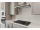 Bright kitchen featuring cooktop, quartz countertop, and stainless vent hood with gray shaker cabinets at 22500 E Orchard Ln, Queen Creek, AZ 85142