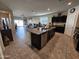 Open kitchen with an island, granite countertops, and dark cabinets at 44394 W Palo Aliso Way, Maricopa, AZ 85138