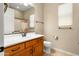 Bathroom with single sink vanity, warm colored cabinets, toilet, blinds, and tub at 26822 W Oraibi Dr, Buckeye, AZ 85396