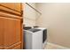 Laundry room with white washer and dryer next to wooden cabinets and rod at 26822 W Oraibi Dr, Buckeye, AZ 85396