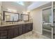 This bathroom features double sinks with granite counters, an arched window and a view to the main bedroom at 11085 E Becker E Ln, Scottsdale, AZ 85259