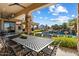 Covered patio with large table and chairs, with an outdoor kitchen, pool and mountain views beyond at 13141 E Cibola Rd, Scottsdale, AZ 85259
