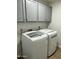Bright laundry room featuring a washer and dryer with gray cabinets above for convenient storage solutions at 3244 E Hononegh Dr, Phoenix, AZ 85050