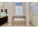 Large bathroom with a round soaking tub and a decorative tile surround at 24002 S 201St Ct, Queen Creek, AZ 85142