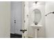 Charming powder room featuring a pedestal sink, oval mirror, and stylish lighting fixtures, adjacent to the front door at 2542 N Riley Rd, Buckeye, AZ 85396