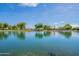 Tranquil lake view showcasing a community clubhouse and green spaces at 4718 E Thunderheart Trl # 103, Gilbert, AZ 85297