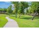 Walking path winds through a lush green park with mature trees at 4718 E Thunderheart Trl # 103, Gilbert, AZ 85297