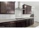 Kitchen featuring dark wood cabinets, stainless vent hood, white subway tile, and quartz countertops at 4918 W Beryl Ave, Glendale, AZ 85302