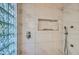 Spa-like shower with marble tile, glass block window, and built-in shelves at 6444 E Paradise Ln, Scottsdale, AZ 85254