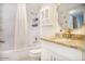 Clean bathroom with white tiled tub, vanity, granite countertop and a decorative round mirror at 7970 E Camelback Rd # 101, Scottsdale, AZ 85251