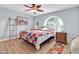 Bedroom with ceiling fan, wood floors, and arched window, offering abundant natural light at 7960 E Madero Ave, Mesa, AZ 85209