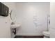 Simple bathroom with a wall sink, round mirror, wooden floor, and mounted hand towel bar at 813 E Glendale Ave, Phoenix, AZ 85020