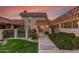 View of the home's front entrance with an iron gate, walkway, and a well-manicured yard, all under a colorful sky at 9734 N 105Th Dr, Sun City, AZ 85351