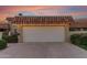 Attached two-car garage featuring white doors, lighting, a tile roof, and landscaping against a colorful dusk sky at 9734 N 105Th Dr, Sun City, AZ 85351