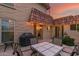 Outdoor patio area featuring a grill, seating, and access to the home, set against a backdrop of a colorful sunset at 9734 N 105Th Dr, Sun City, AZ 85351