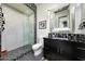 Modern bathroom with glass-enclosed shower, black and white tile accents, and sleek black vanity at 10878 E Sundance Trl, Scottsdale, AZ 85262