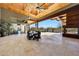 Spacious outdoor dining area on a covered patio with stone floors and a fireplace overlooking the pool at 10878 E Sundance Trl, Scottsdale, AZ 85262