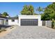 Attached two-car garage with gray door and white brick exterior; modern landscaping, wide gray brick driveway at 342 E Orangewood Ave, Phoenix, AZ 85020