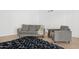 Cozy living room with a gray sofa and chair, plush black rug, and neutral decor, set on hardwood floors at 342 E Orangewood Ave, Phoenix, AZ 85020