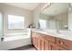 Well-lit bathroom with a double vanity, large mirror, and soaking tub for a spa-like experience at 8808 W State Ave, Glendale, AZ 85305