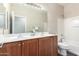 The bathroom features a double vanity and a shower-tub combo with wood cabinets and tile floors at 8808 W State Ave, Glendale, AZ 85305