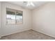 This bedroom features neutral walls and carpet and a large window with a view of the backyard at 8808 W State Ave, Glendale, AZ 85305