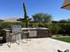 Modern outdoor kitchen with grill, cabinetry, and barstools at 9771 E Roadrunner Dr, Scottsdale, AZ 85262