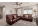 Comfortable living room featuring brown leather couches and a ceiling fan at 19122 W Solano Dr, Litchfield Park, AZ 85340