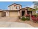 Charming two-story home featuring a brick-accented entrance, tan stucco, and an attached two-car garage at 19544 W Lincoln St, Buckeye, AZ 85326
