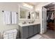 Double vanity bathroom with gray cabinets and a walk-in closet at 30052 N Desert Willow Blvd, San Tan Valley, AZ 85143